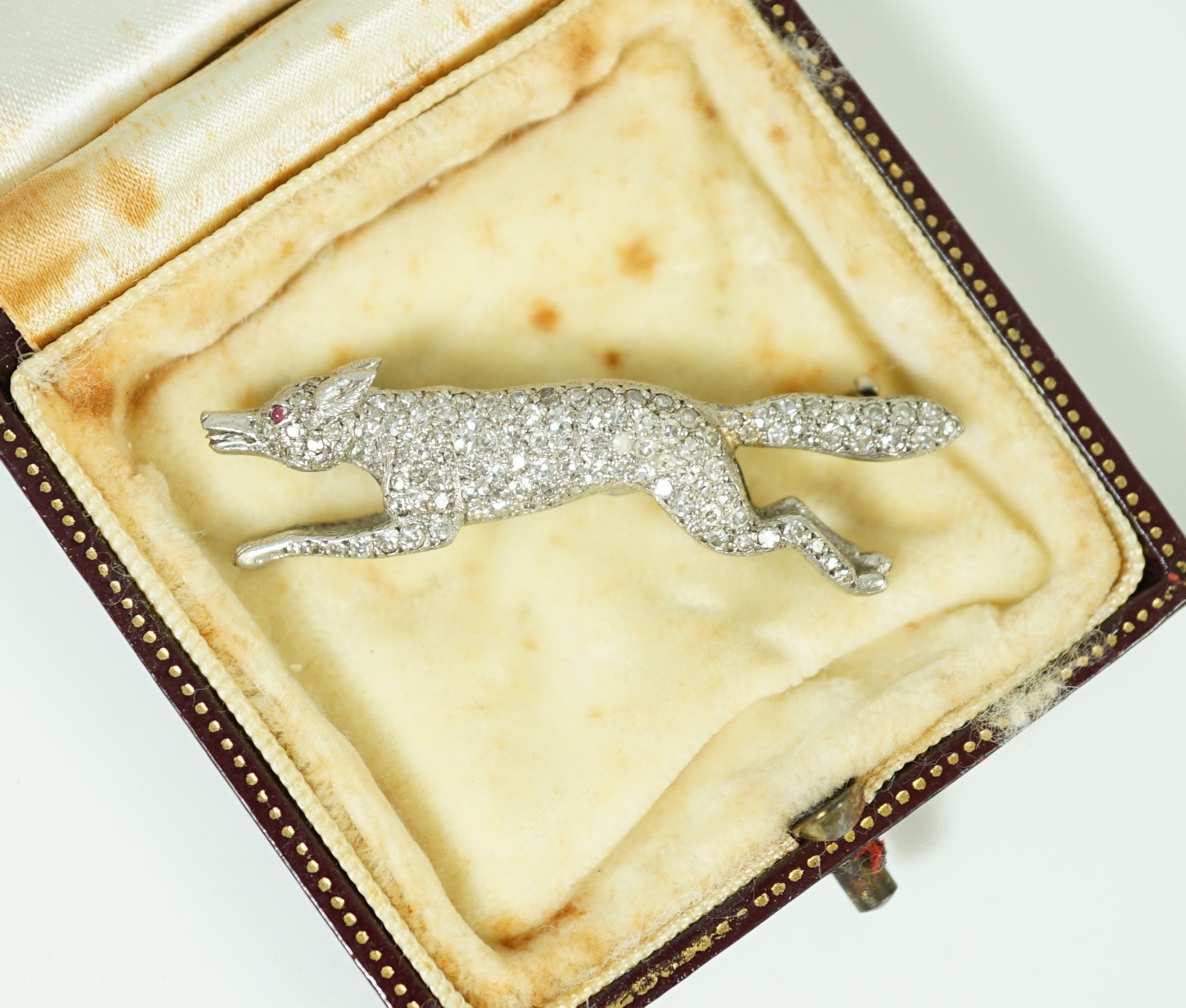 A Victorian style white gold, diamond encrusted and cabochon garnet set brooch, modelled as a running fox